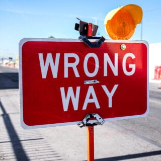 Ein rotes Verkehrsschild mit einer orangenen Warnleute, auf dem "Wrong way" steht.