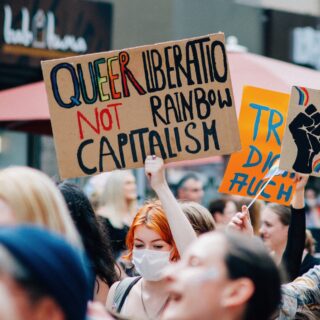 Demo, auf der ein Schild zu lesen ist: "Queer liberation, not rainbow capitalism!"