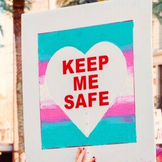 ein Foto von einem Demoplakat. Darauf gemalt die trans pride flagge und darin ein Herz mit roter Schrift. Der Text sagt "Keep Me Safe".